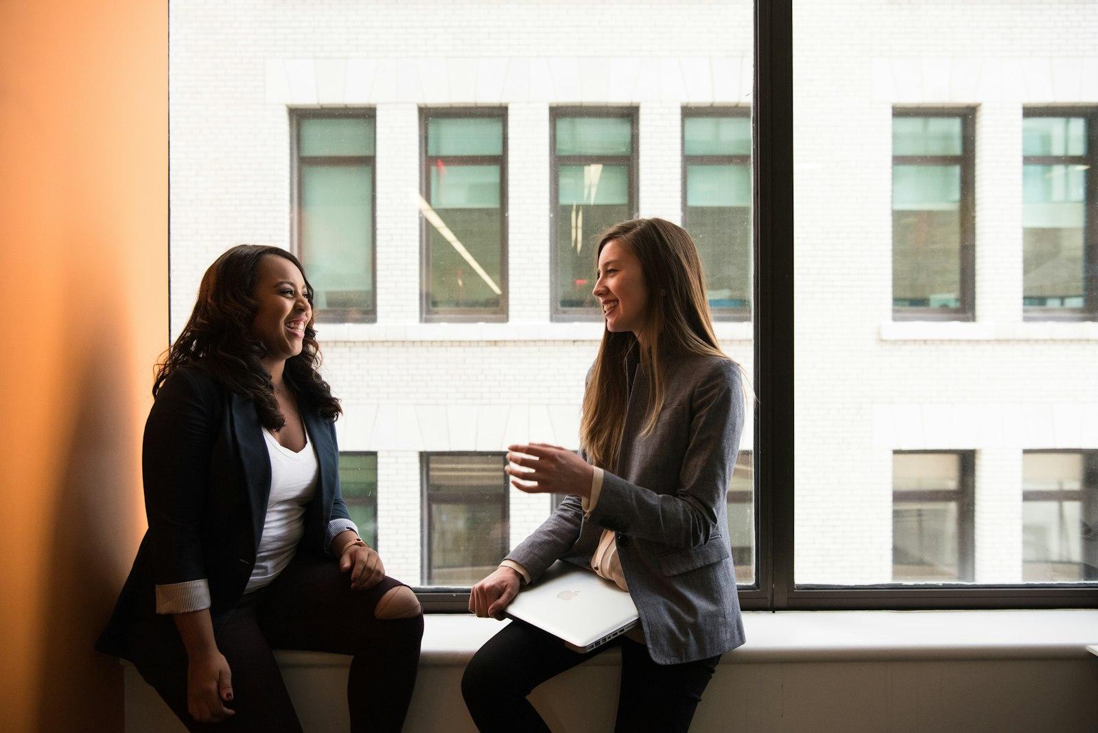 Two adults laughing together beside a window