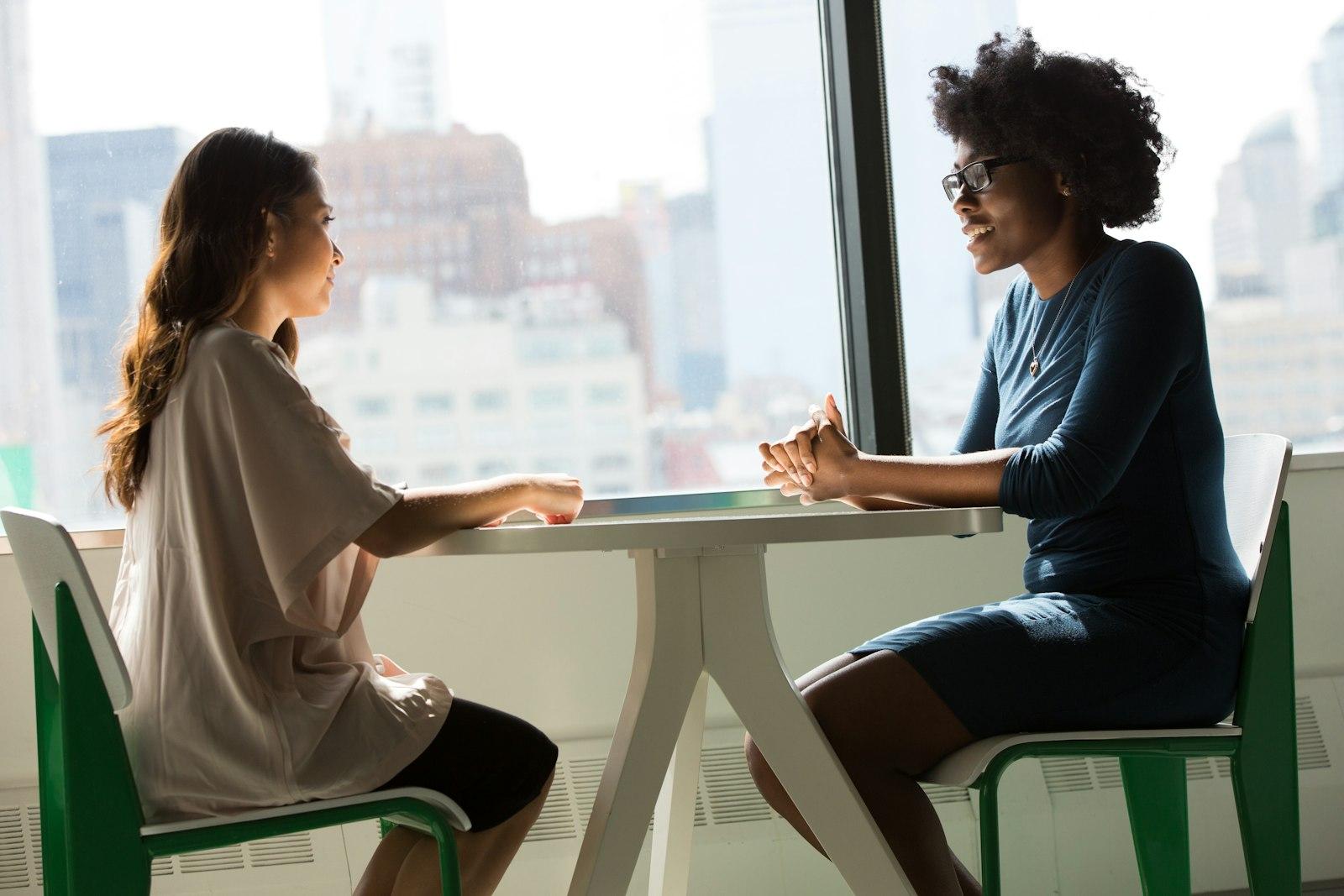 Two adults talking across a table in a bright room