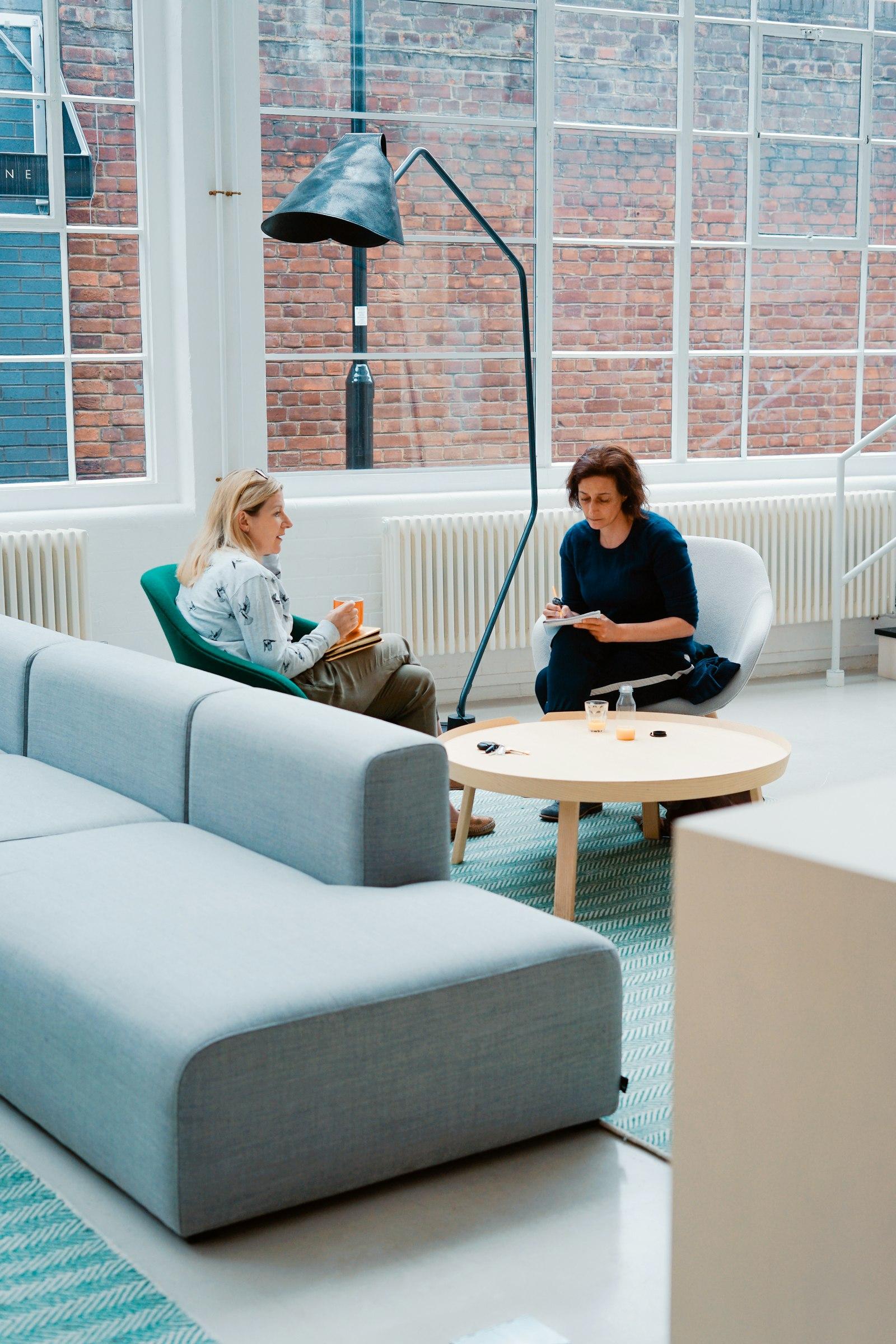Two adults meeting in a bright room, one taking notes